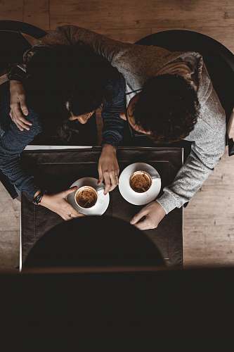 person man and woman sitting on floor while holding cups on table people