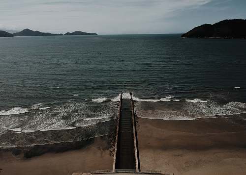 water black plank walkway beside body of water nature