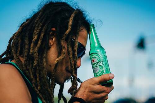 human person holding Heineken beer bottle bottle