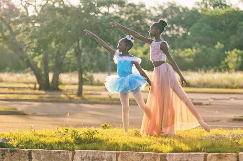 human two girls wearing blue and peach dresses dancing on green grass people