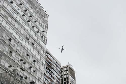 black-and-white low-angle photography of airliner and high-rise buildings grey