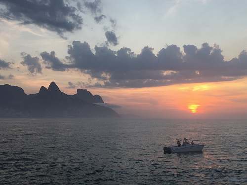 brazil person riding on boat surrounded with body of water during golden hour praia do arpoador