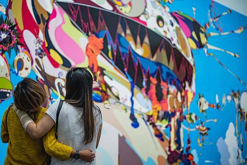 painting two women looking in front of wall painting human
