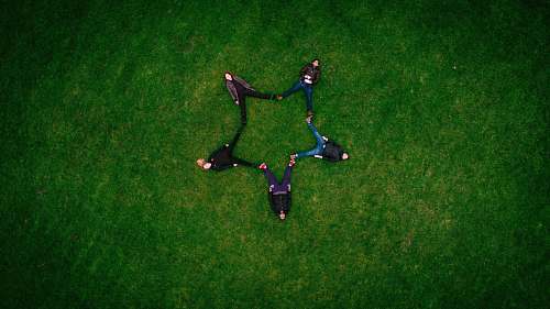 green five people laying on grass field making star sign field