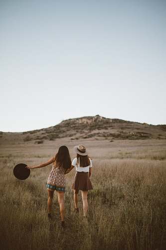 woman two women walking around near mountain at daytime field