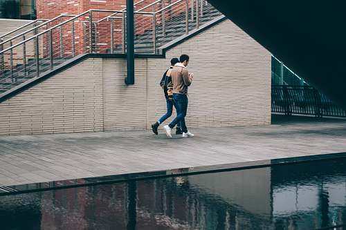 people two man walking beside stair and body of water at daytime human