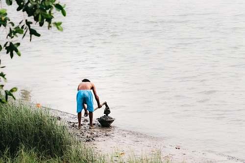 clothing man digging on shoreline using draw hoe shorts