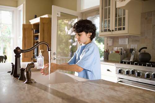 human boy in blue polo shirt standing in front of sink sink