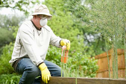 human man in white long sleeve shirt and blue denim jeans sitting on brown wooden fence during outdoors