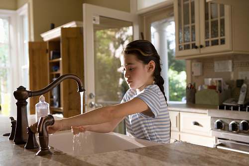 human woman in blue and white stripe shirt washing her hands sink