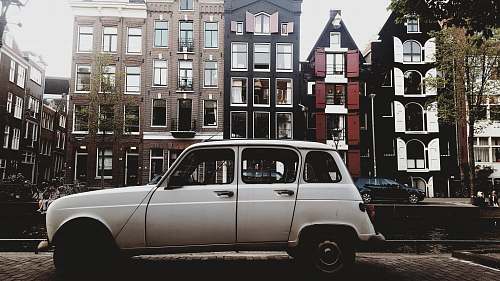 vehicle white vehicle parked beside concrete buildings transportation
