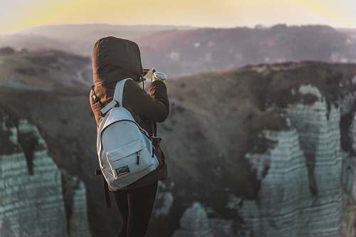 sunset person standing near cliff holding camera person