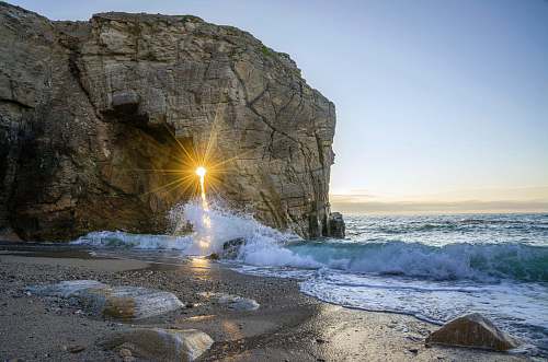 sand sea wave splashing in seashore beside mountain brittany