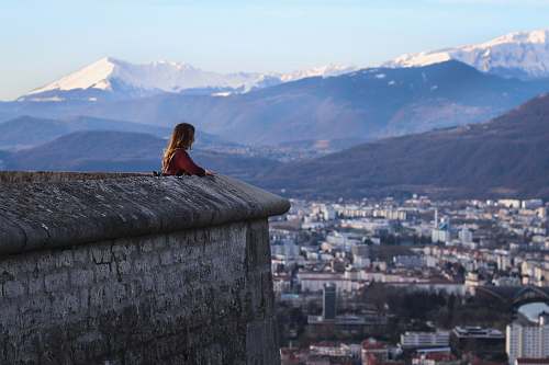 view woman standing near high rise buildings and mountains during daytime grenoble