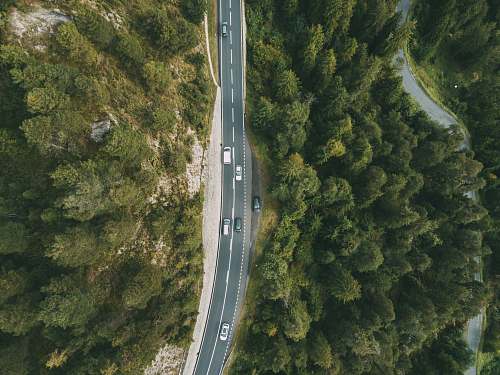 road aerial photography of vehicle passing by highway between green trees switzerland