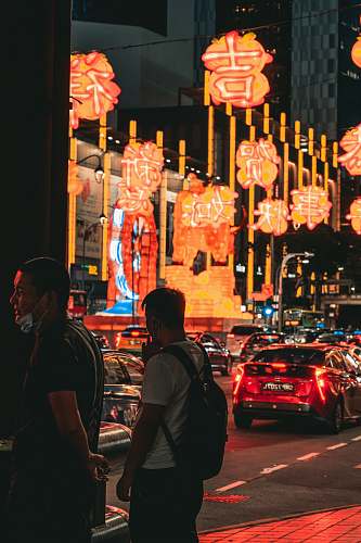 person man in black jacket standing near red car during night time automobile