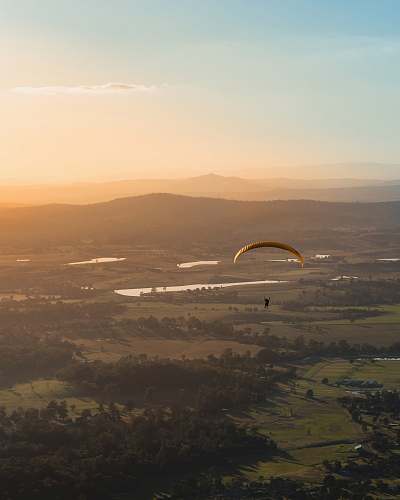 paraglide person paragliding above countryside during daytime gold coast