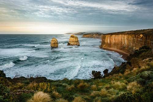 sea HDR photo of two rock formation on sea under cloudy sky during daytime water