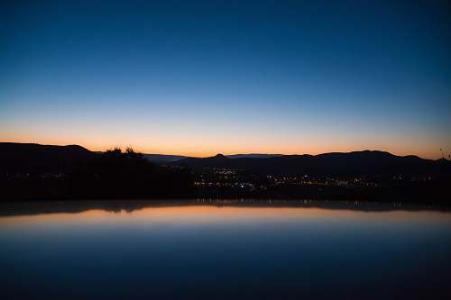 sky calm lake waters reflecting city and trees and clear sky sunrise