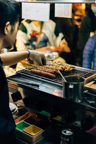 person man barbecuing skewered sausages human