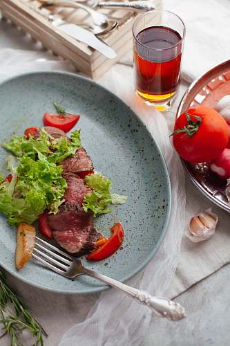 dish meat with sliced vegetables on plate fork