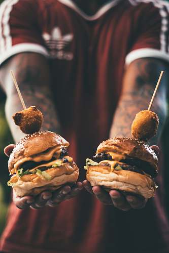 people person holding two cheese hamburgers person