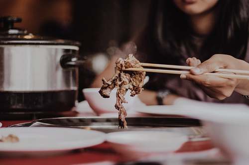 meal woman holding beige chopsticks meat