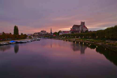 city calm body of water near village during golden hour sky