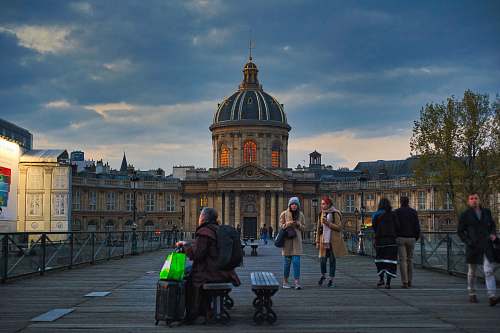 person people walking and sitting in front of brown concrete dome building during golden hour pedestrian