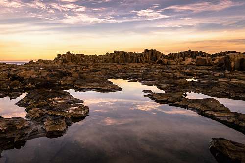 rocks calm body of water and overlooking mountain bombo quarry