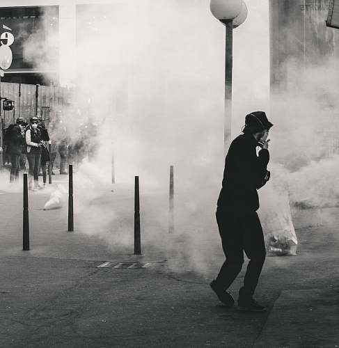human grayscale photo of man near smoke lyon