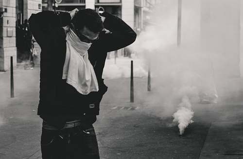 human man standing and covering his face using shirt smoke