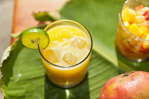 food clear drinking glass with yellow liquid and sliced of lemon fruit