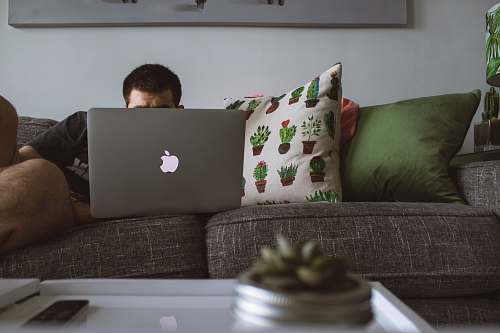 couch man using MacBook sat on sofa man working