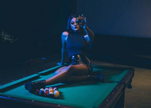 indoors woman sitting on top of a pool table room