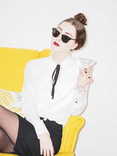 accessories woman in white dress shirt and black skirt sitting on yellow couch sunglasses