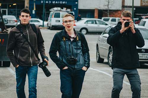 apparel man in black jacket holding black dslr camera coat