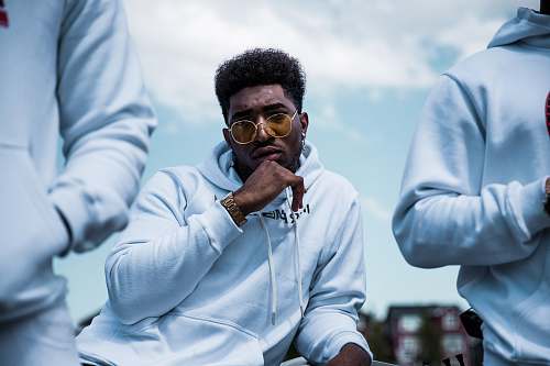 person shallow focus photo of man in white pullover hoodie wearing brown sunglasses hair