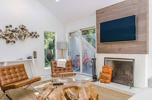 furniture two tufted brown leather chairs in front of brown wood stump center table fireplace