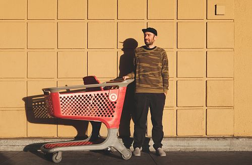 man standing near red and gray shopping cart