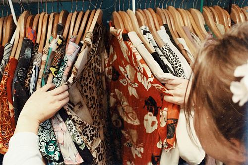 person holding assorted clothes in wooden hanger