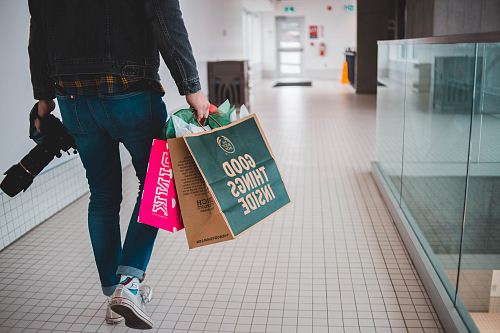 person walking while carrying a camera and paper bags
