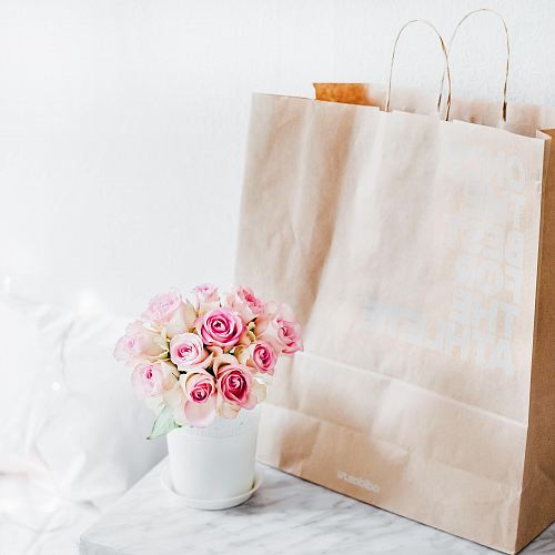 pink rose bouquet beside brown paper bag