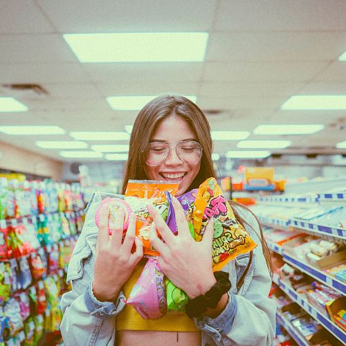 smiling woman holding pack of food inside grocery store