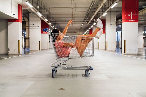 woman sitting in shopping cart at parking lot
