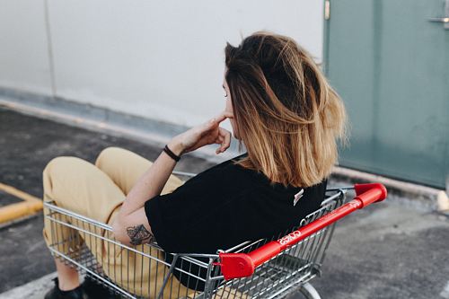 woman sitting on shopping cart near the wall