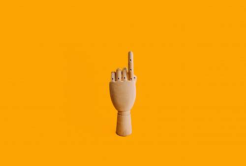 yellow beige wooden hand sculpture with orange background manikin