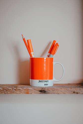 food markers in mug on brown surface cup