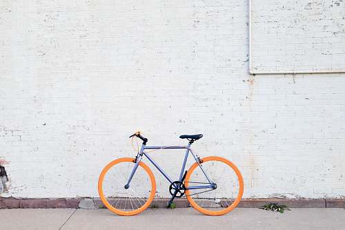 bicycle yellow and purple bicycle near white wall at daytime bike