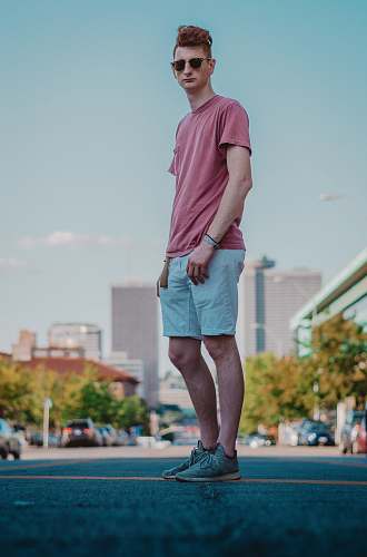 clothing man in red t-shirt and gray shorts standing on field during daytime shorts